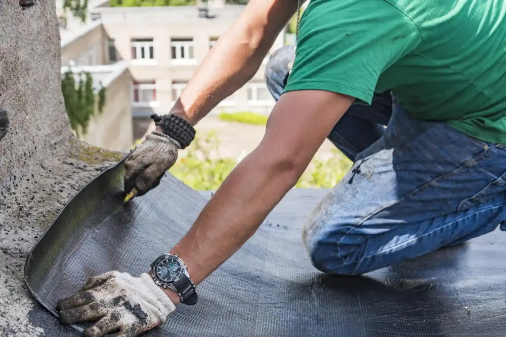 Homem aplicando sistema de impermeabilização em uma superfície no telhado, importante para proteger contra infiltrações e surtos de água.