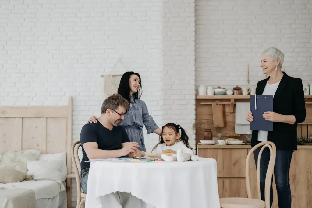 Assistente social interagindo com uma família em ambiente doméstico, demonstrando preparação do curso de Assistente Social para trabalhar com famílias e comunidades.