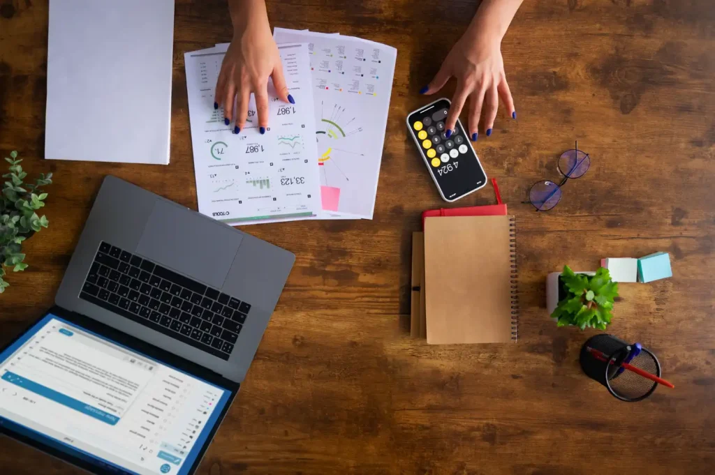 Pessoa analisando demonstrações contábeis e dados financeiros em uma mesa de trabalho, destacando a importância de usar demonstrações contábeis para tomar decisões estratégicas.