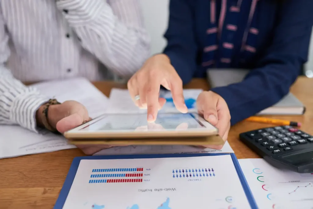 Duas pessoas analisando demonstrativos financeiros com um tablet, evidenciando erros comuns na interpretação de demonstrativos financeiros.