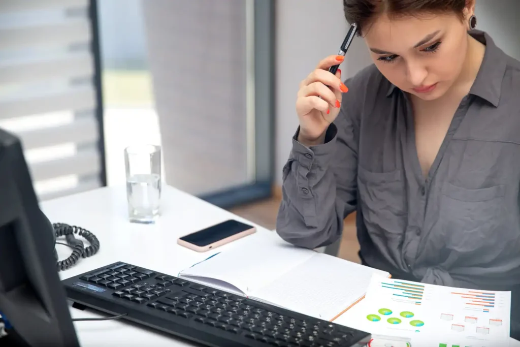 Mulher analisando indicadores financeiros para gestores, com gráficos e papéis de análise financeira na mesa, foco na importância dos indicadores para a gestão.