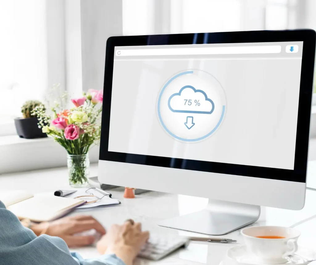 Backup de Dados: Por Que Toda PME Deveria Ter um Plano: Tela de computador em um escritório com ícone de nuvem e percentual de 75% ao lado de mesa de trabalho, documentos e pessoas, tema de backup de dados.