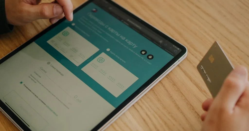 Pessoa usando tablet para configurar pagamento e logística no e-commerce, com cartão bancário na mesa e seleção de etapas de compra e envio